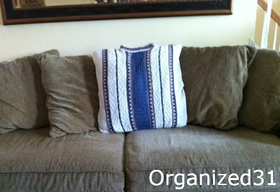 one light grey and blue striped sweater pillow on brown couch