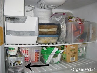 freezer shelves with black arrow pointing to clear organizing container 