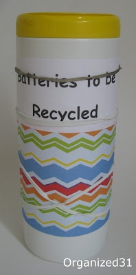 a repurposed wipes container covered in decorative paper and a label with text reading Batteries to be Recycled, with a rubberband around the label