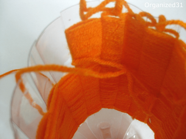 showing where to tie off the orange yarn in a plastic bottle