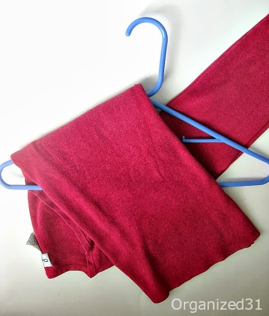 showing how to fold a sweater on a blue hanger