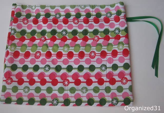 a Christmas fabric gift bag with a green ribbon on it