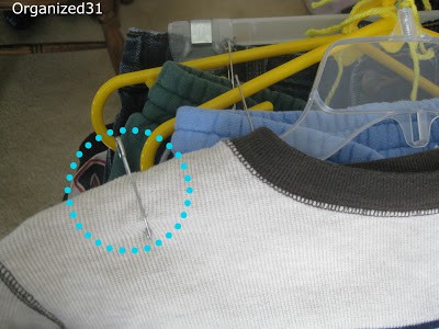 a closeup of a blue circle showing a safety pin attaching a shirt to a hanger