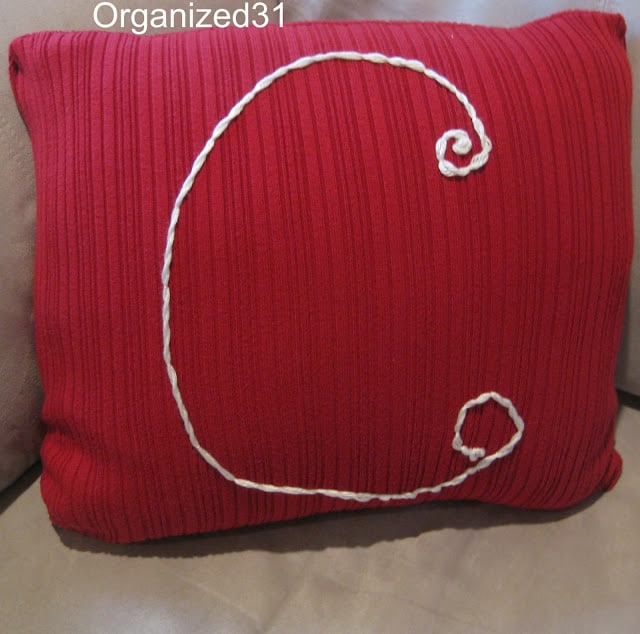 a red sweater pillow with the letter C on it