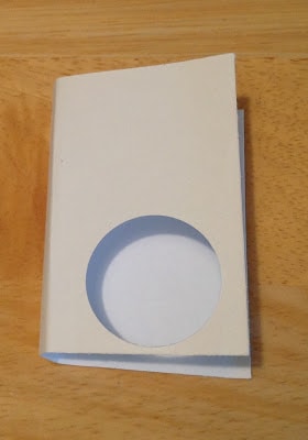a folded white paper with a circle cut out of it