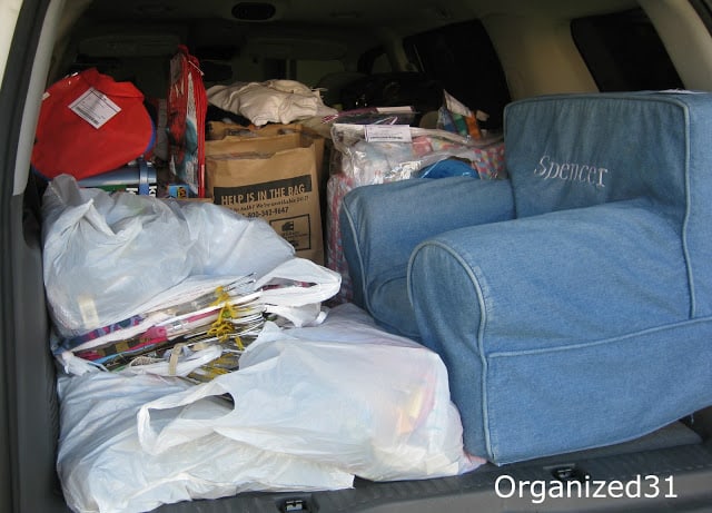 a chair, plastic bags and boxes in the back of a car