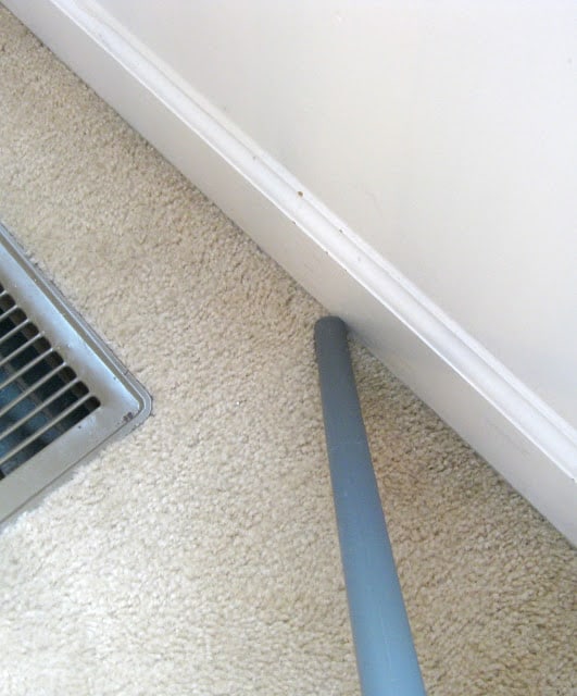 vacuum hose near baseboards and floor vent