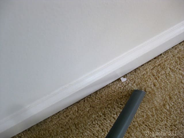 small white scrap on floor near baseboard and vacuum hose