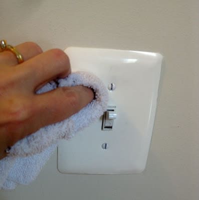woman's hand with white cloth cleaning light plate