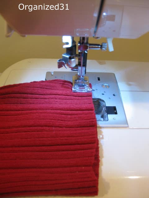 using a sewing machine to stitch a red sweater
