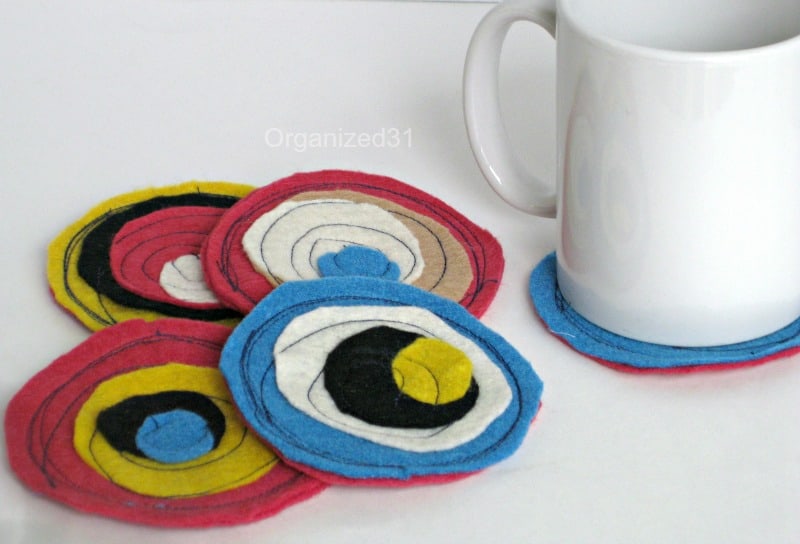 red, white, blue, yellow, and black circular coasters, one with a white mug on top.