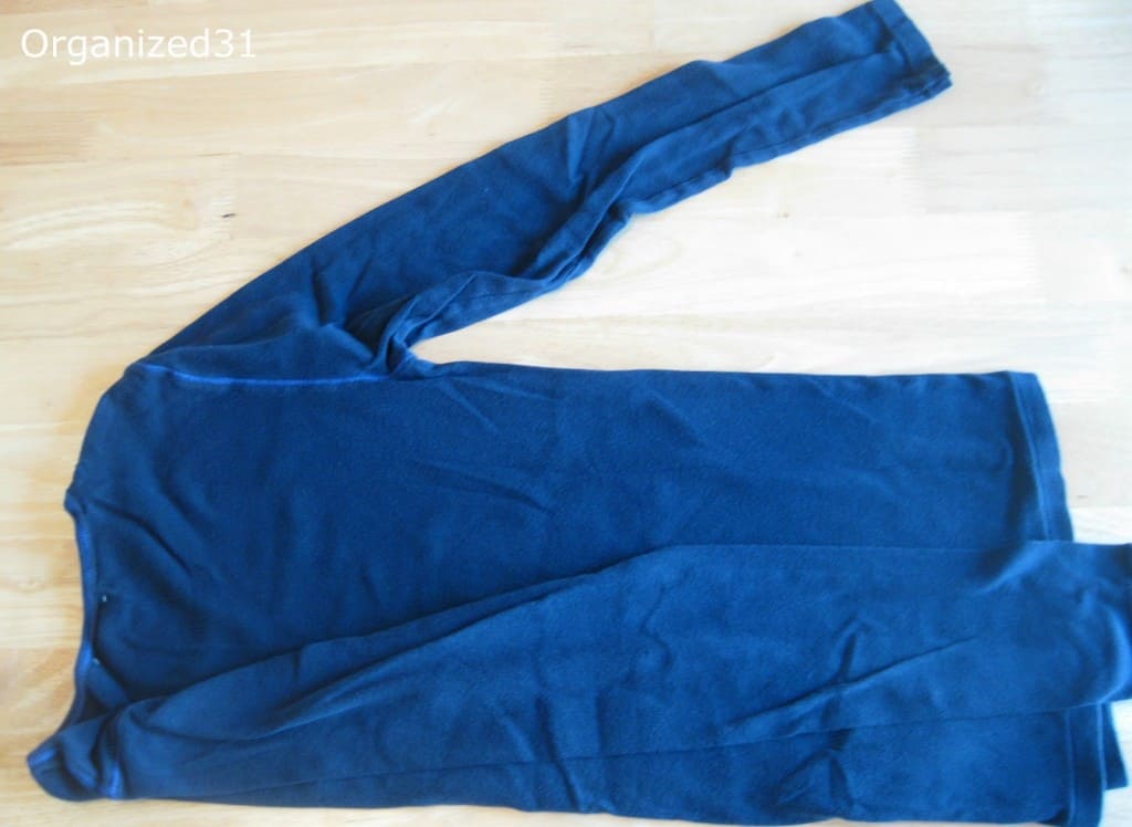 overhead view of one sleeve of blue shirt folded in and other spread out on wood table.