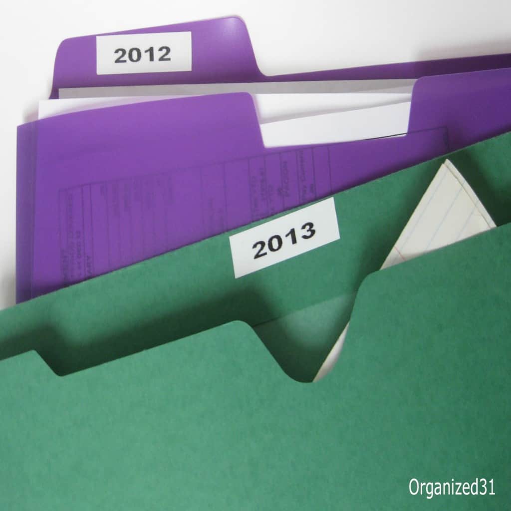 purple and green folders holding papers and labeled with "2012" and "2013"