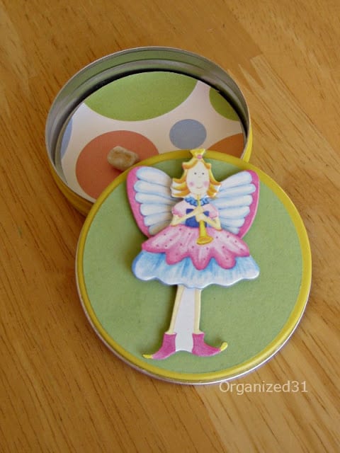 an image of a fairy on a tin lid with a tooth in the tin