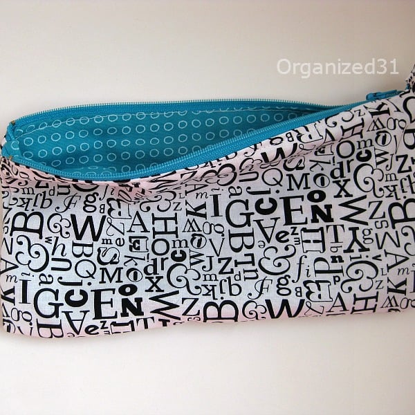fabric pencil pouch with outside covered in black letters and inside with blue polka dots.