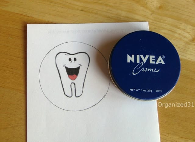 an image of a tooth on a white paper next to a Nivea Creme tin