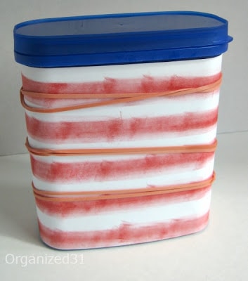 rubber bands holding on a red and white striped paper wrapped around a can with a blue lid