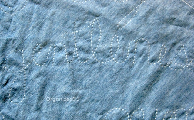 a closeup of the word gentleness sown on a blue quilt