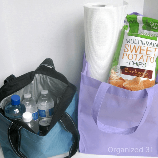 snacks, water and paper towels in  purple and blue tote bags