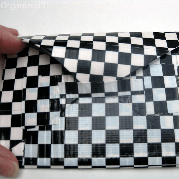 black and white checkered Duck tape wallet with top being tucked into loop closure.