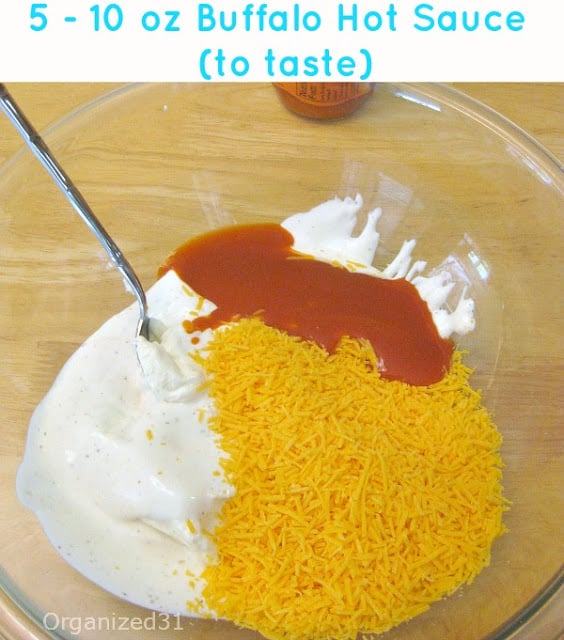 large glass bowl with white cream, shredded cheese and red sauce and metal spoon with title text reading 5 - 10 oz Buffalo Hot Sauce (to taste)