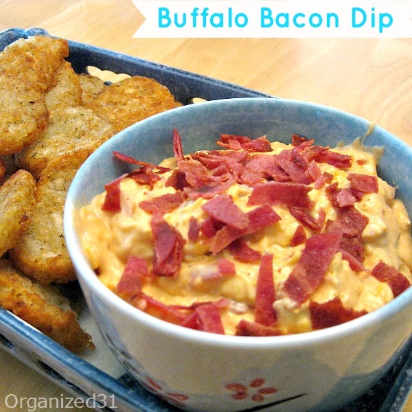 close up of light blue bowl with orange dip with bacon garnish next to potato pieces on blue tray with title text reading Buffalo Bacon Dip