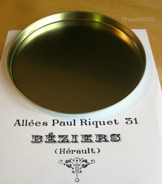 a tin lid on a paper with words on it for a French pharmacy