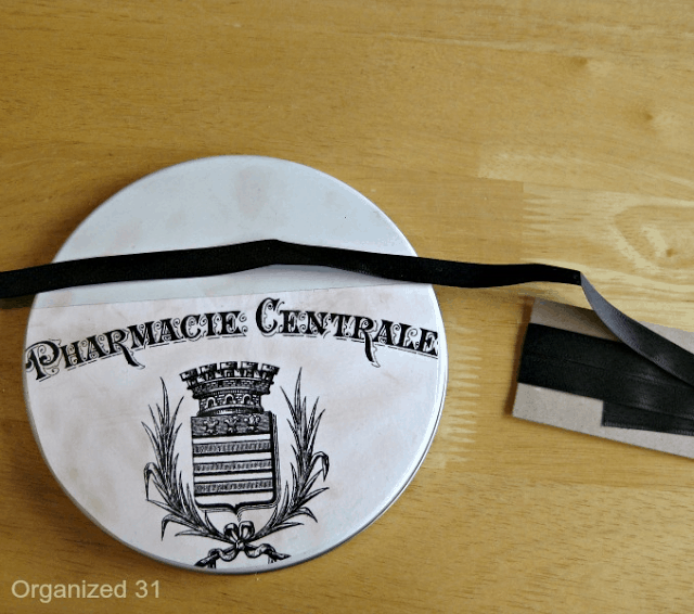 French pharmacy paper on the tin lid next to a ribbon