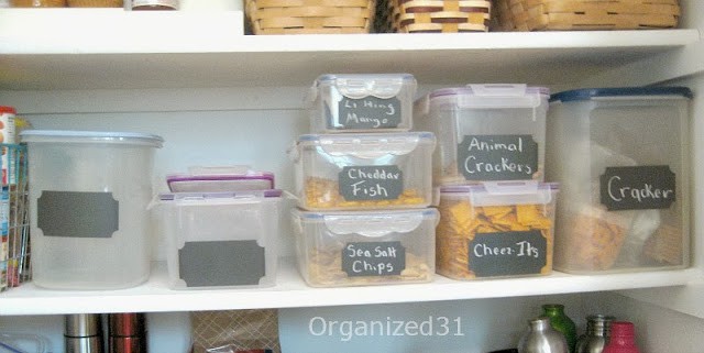 rectangular food storage containers with black chalkboard labels on pantry shelf