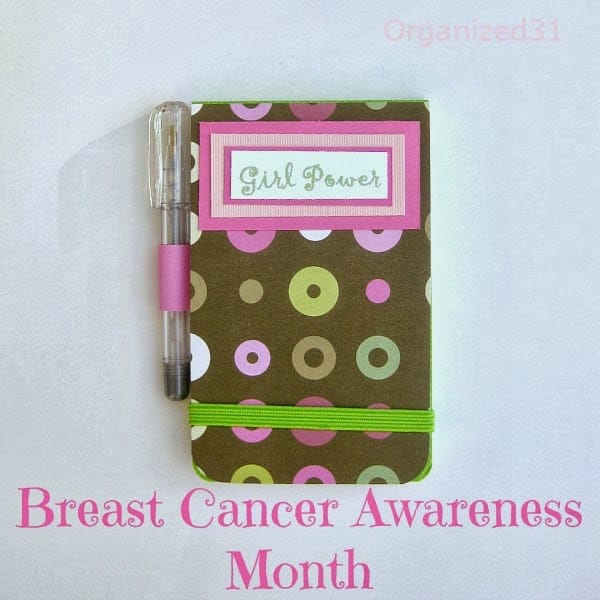 decorated note pad with small pen attached, green elastic strap and label in pink saying "girl power" with title text reading Breast Cancer Awareness