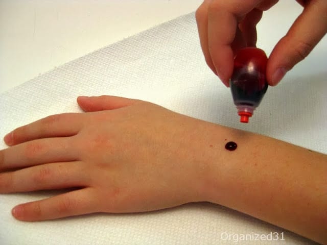 red food coloring being dropped onto forearm