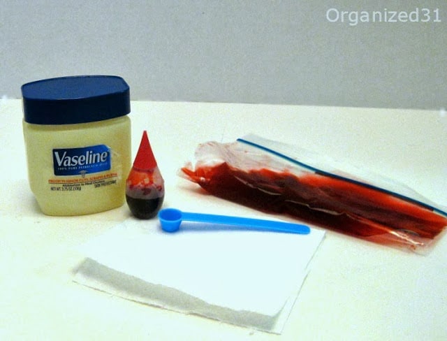 jar of petroleum jelly, bottle of red food dye, small blue scoop and bag of red gel