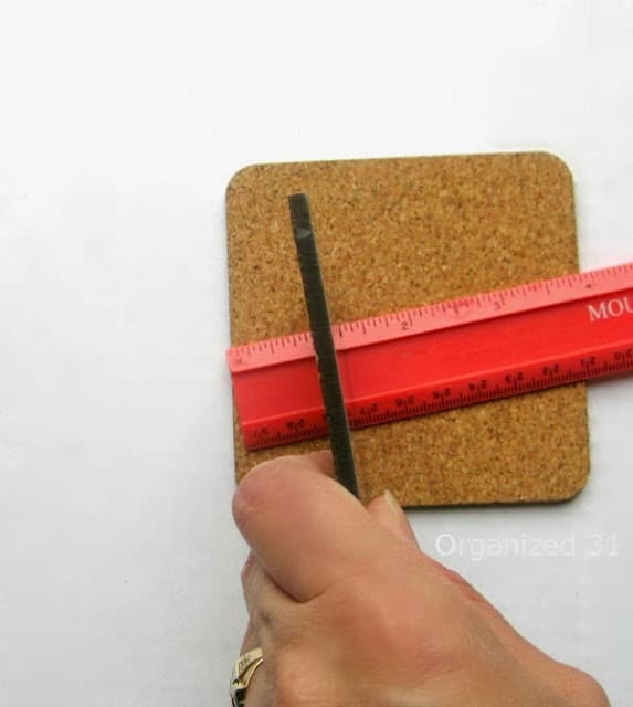 a hand using a ruler to measure a piece of cork