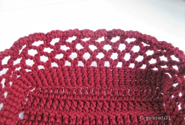 close-up of maroon crocheted cozy with open-weave border.