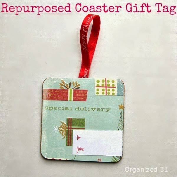 a gift tag decorated with Christmas paper with a red ribbon on it with title text reading Repurposed Coaster Gift Tag