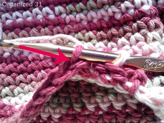an arrow pointing to the needle and loops on a crocheted basket