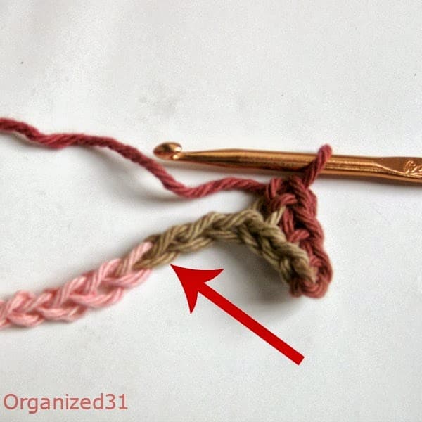 an arrow pointing to a crocheted chain where the yarn changes color