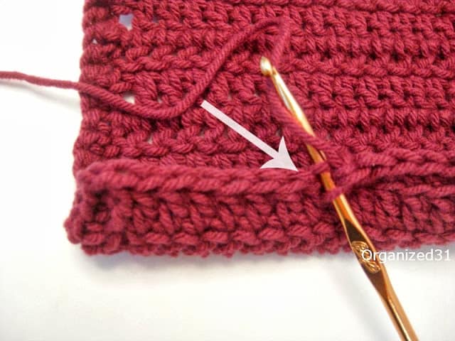 close up of gold crochet needed in maroon crochet square to show particular stitch.