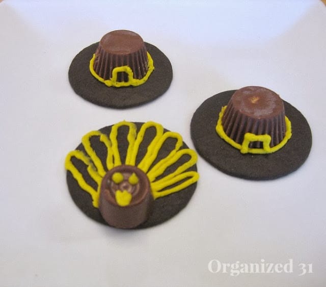 2 cookies decorated to look like a pilgrim hat and one cookie decorated to look like a turkey