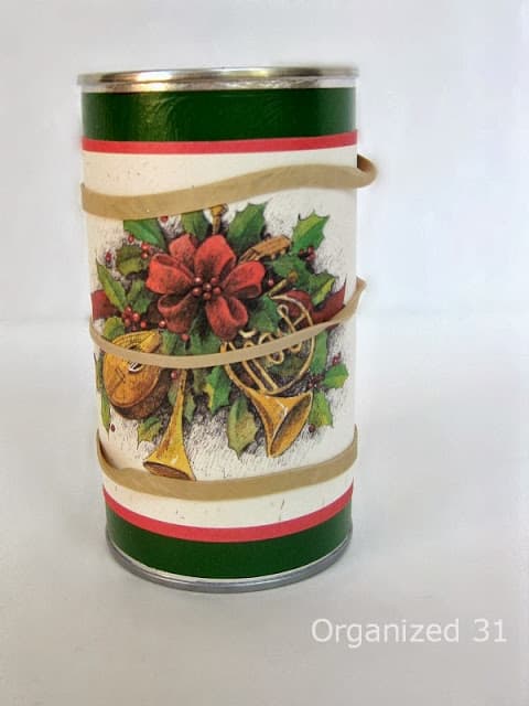 a rubber band wrapped around a Christmas card on a can.