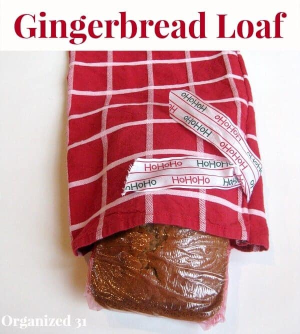 a loaf of gingerbread wrapped in plastic wrap, in a red and white bag with a ribbon on it with text reading hohoho, and title text reading Gingerbread Loaf
