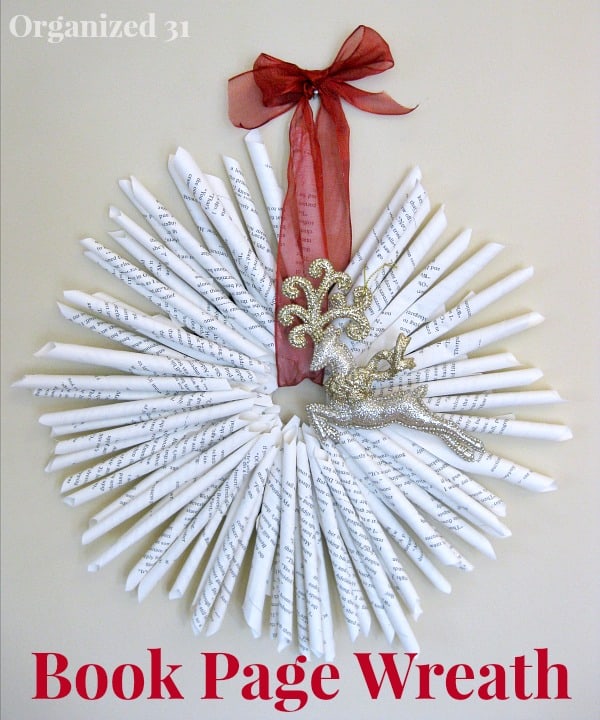 wreath made from rolled up book pages with red ribbon and gold reindeer