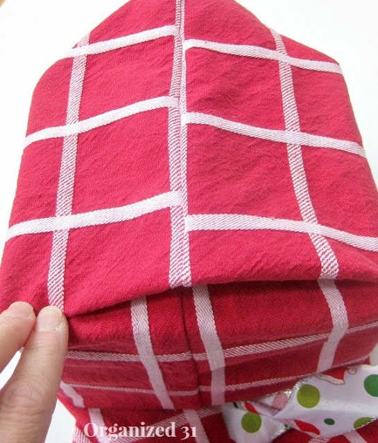 showing how to fold the corners of the red and white fabric gift bag