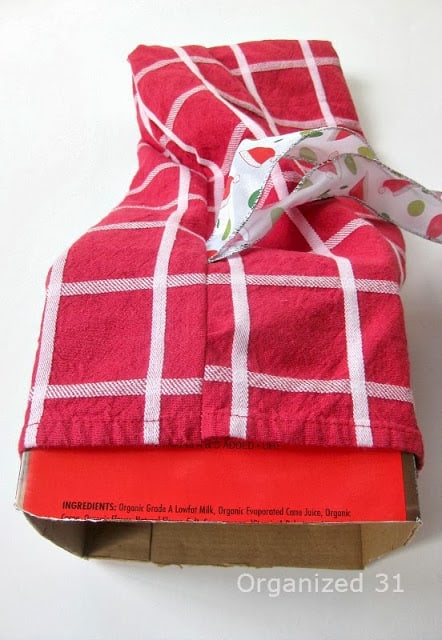 a red and white fabric being slipped over a cardboard box