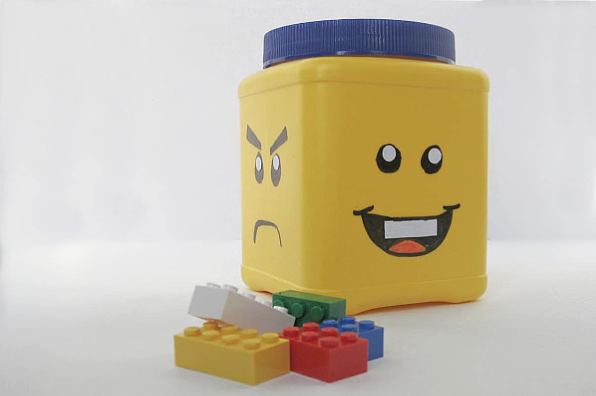 yellow can with blue lid and DIY face to look like LEGO head storage with colorful LEGO blocks.