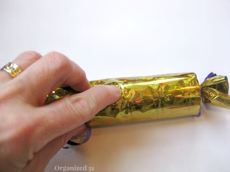 hand holding seam of gold foil  popper on white table