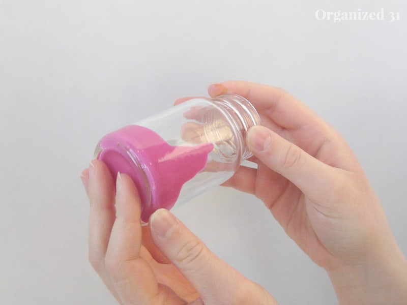 hands holding a jar with pink paint in it