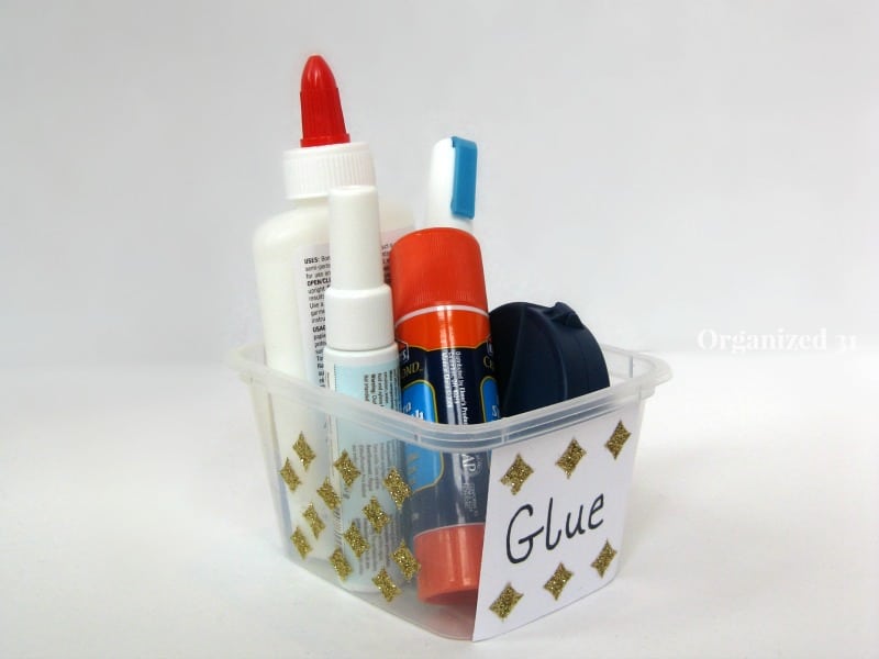 various types of glue in a clear plastic tub decorated with gold diamonds and a label with text reading Glue
