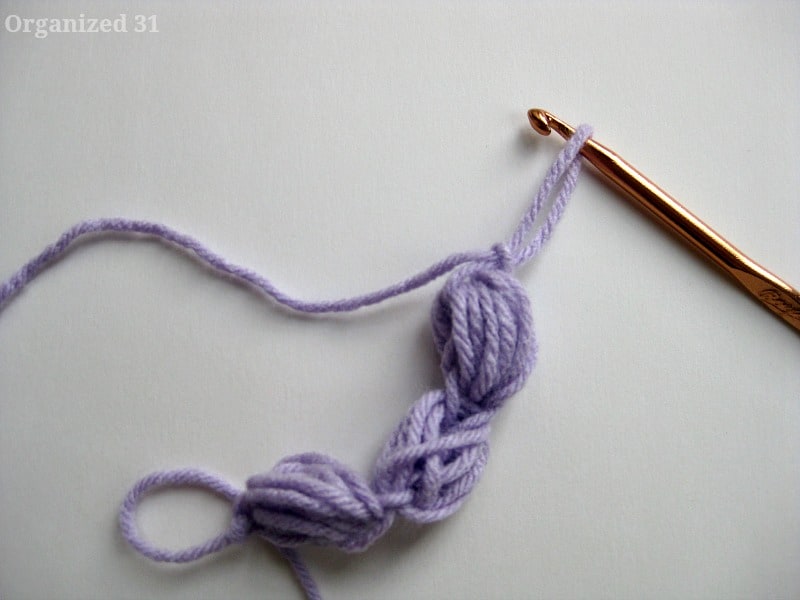 Purple yarn over crochet hook.