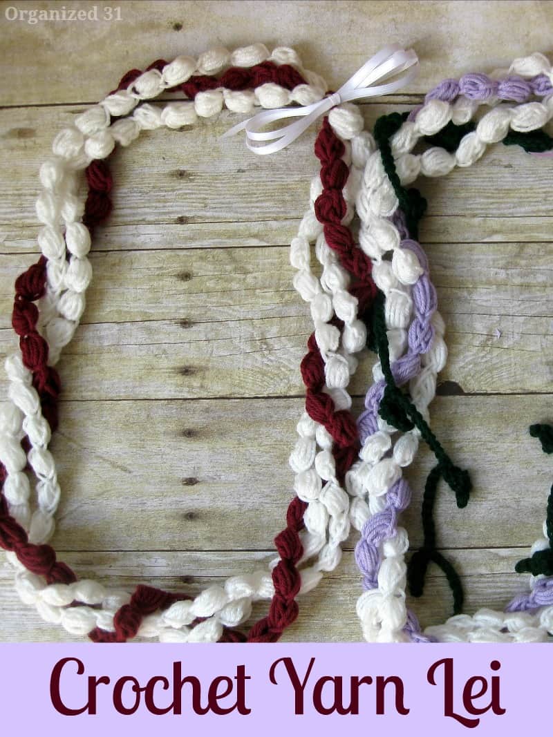 2 crocheted yarn leis with bows on  rustic wood table